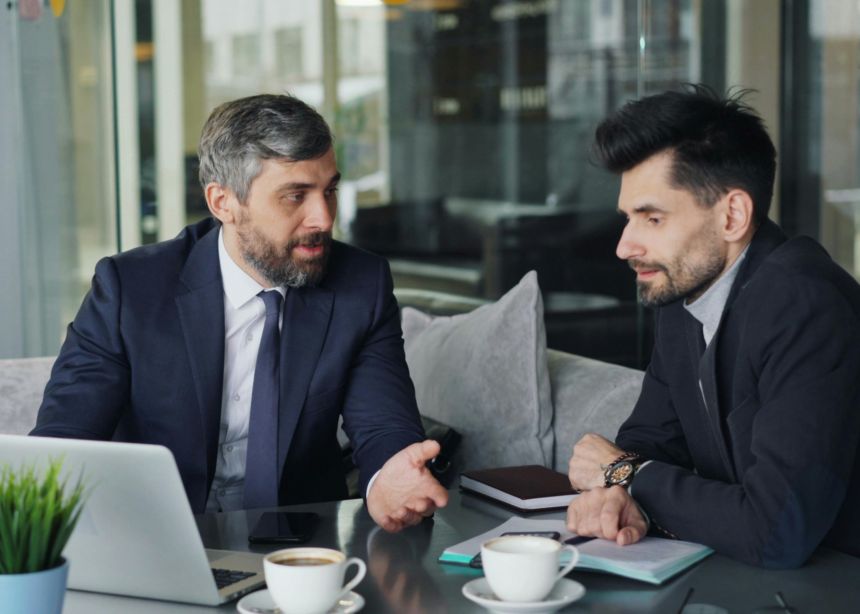 Middle aged man receiving business coaching from grey-haired man